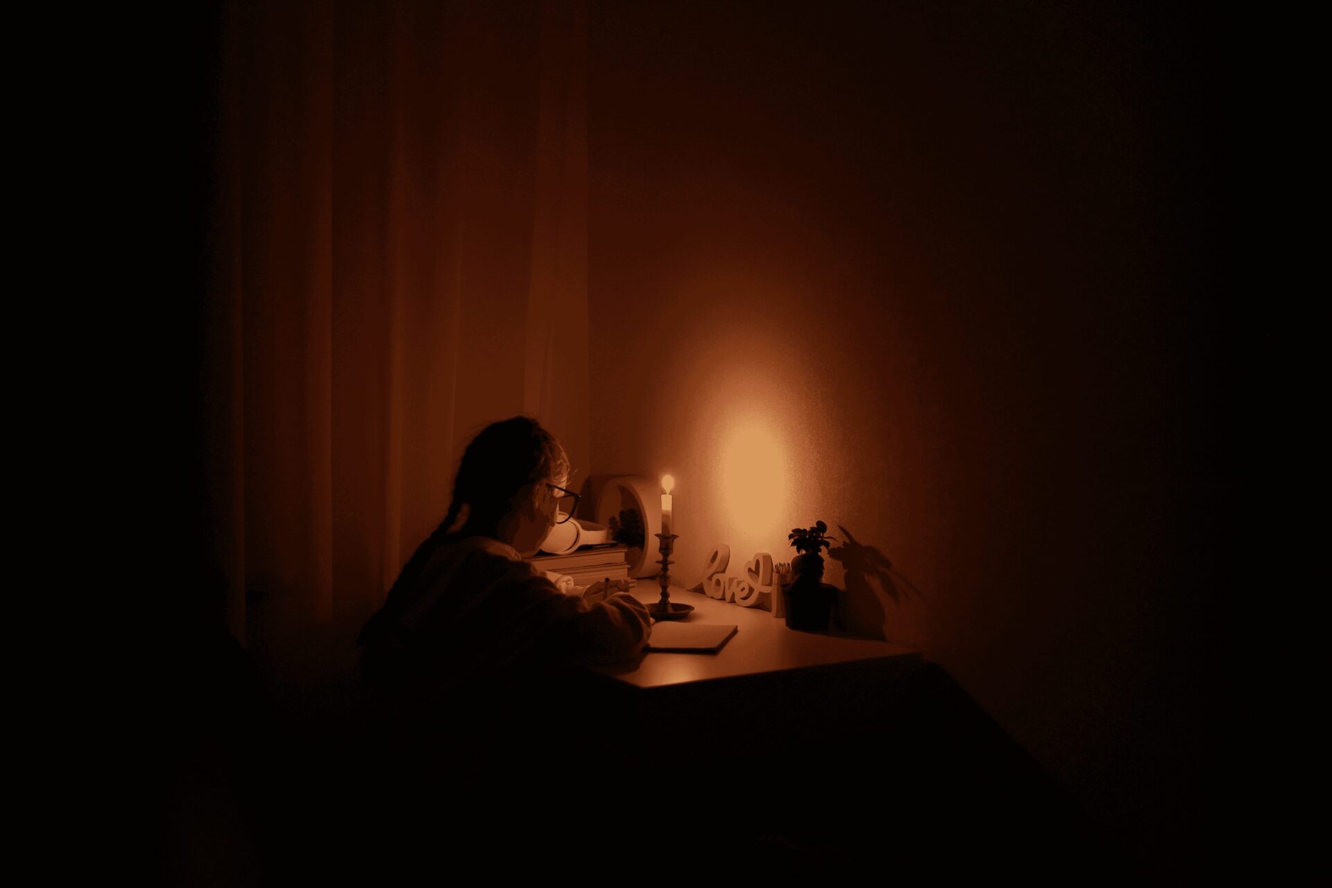 schoolgirl uses candlelight to write and read during power outage, backup generator, electrician near me,backup , generator installation, generator service