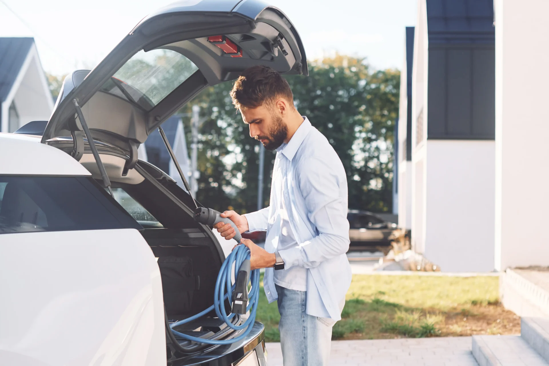 young stylish man taking EV charging Cable from the truck, electric charging at home, ev charging solution, ev electrician near me,